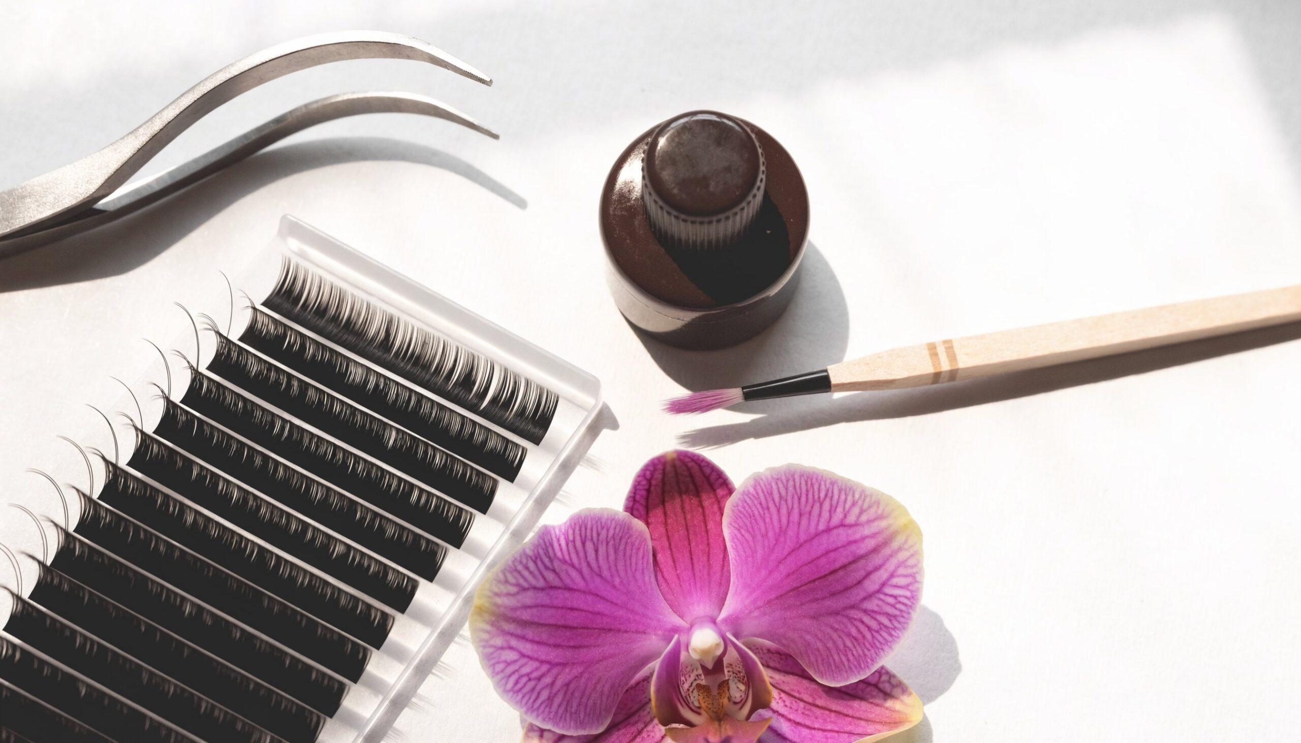 Wimpernwerkzeuge und Volumenfächer für die Volumentechnik auf hellem Untergrund