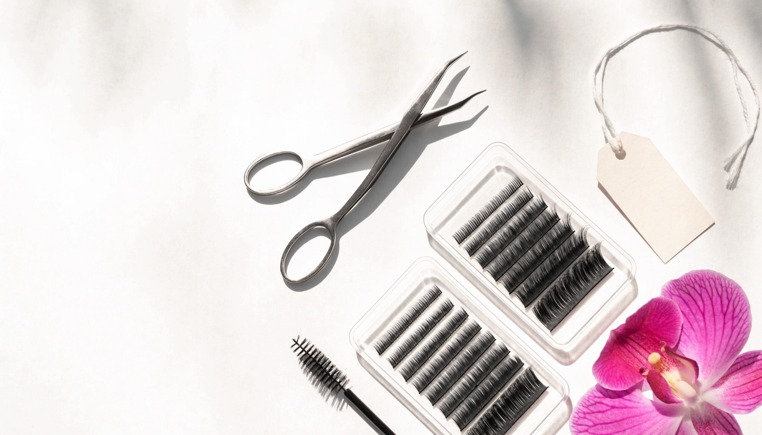 Helles Flatlay mit Wimpernpinzette, Wimpernfächern, Preis-Anhänger und Orchidee – Wimpernverlängerung Preise
