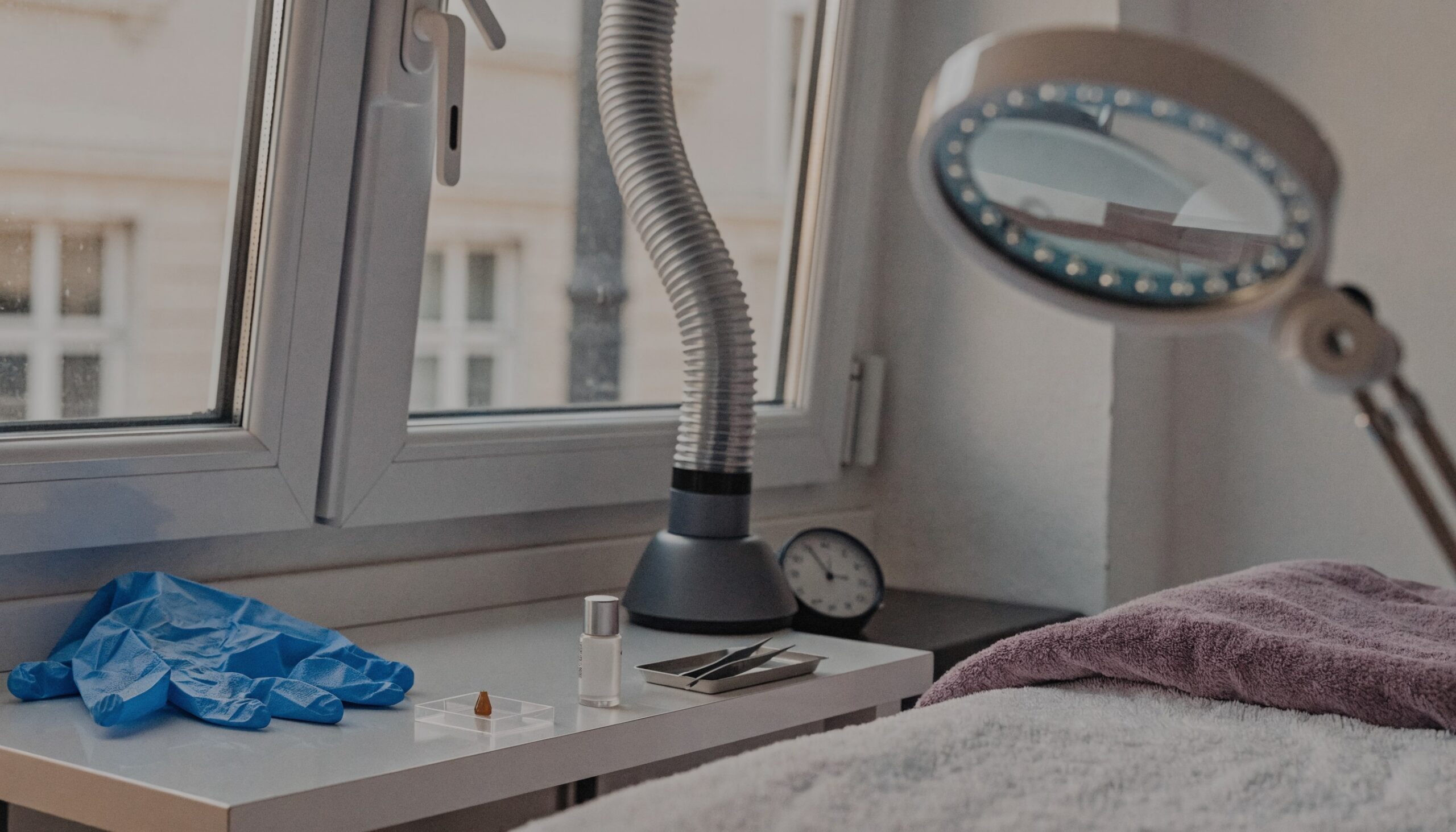 Wimpernkleber Allergie Stylistin: Arbeitsplatz im Wimpernstudio mit Nitrilhandschuhen, kleinem Klebertropfen, Absaugung und Lupenleuchte am gekippten Fenster