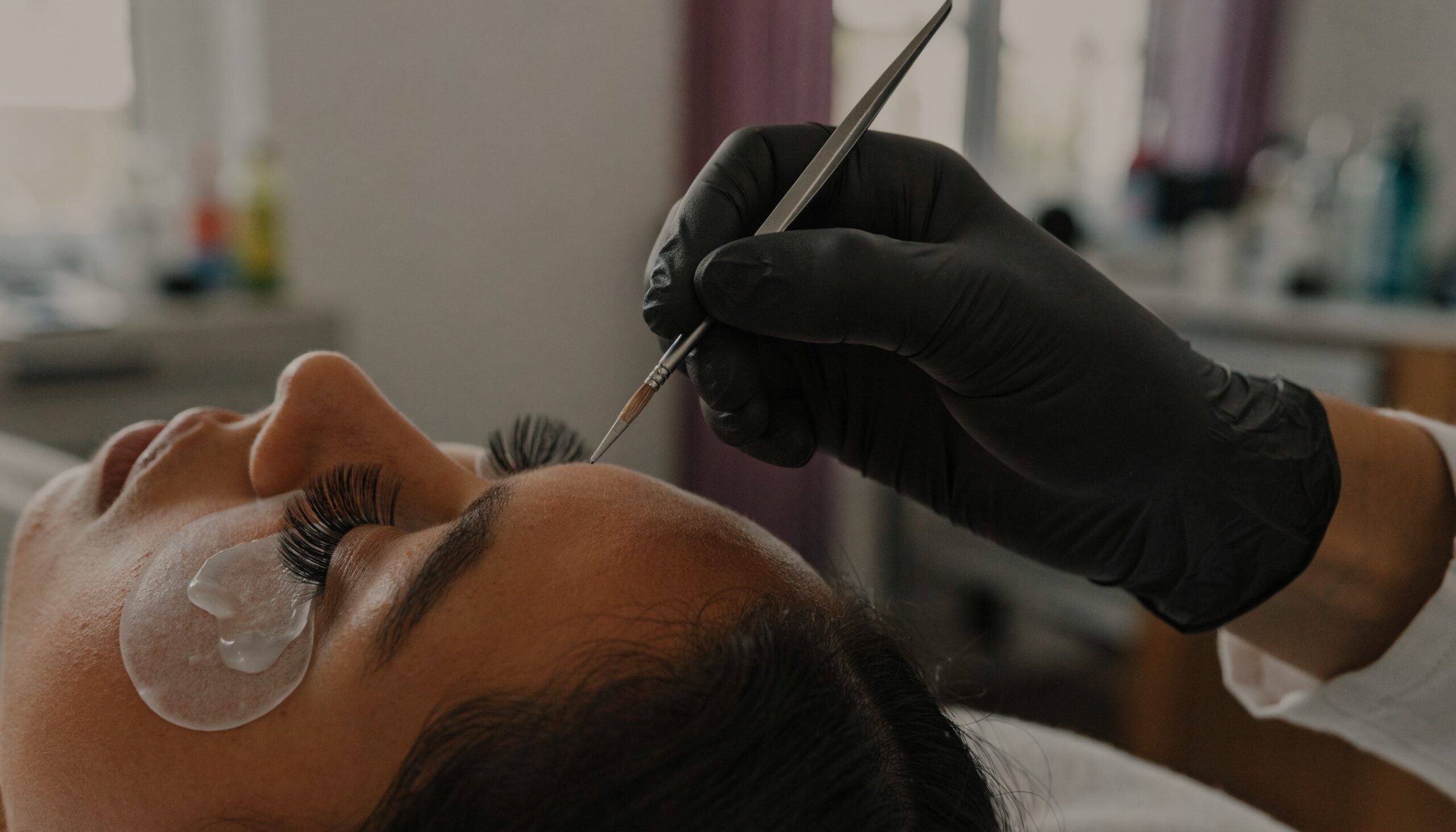 Wimpernverlängerung entfernen in Wien: Stylistin löst bei geschlossenem Auge mit Augenpad die Extensions am Wimpernansatz